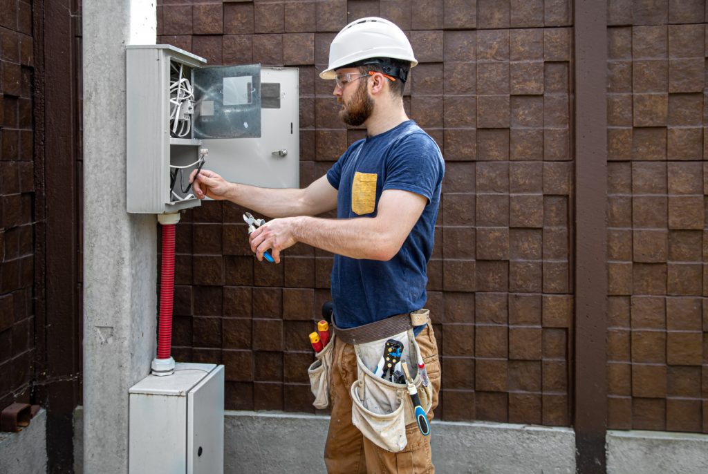 electrician-builder-work-examines-cable-connection-electrical-line-fuselage-industrial-switchboard-professional-overalls-with-electrician-s-tool-1-1024x686